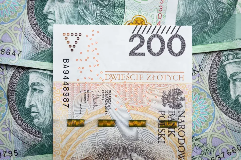 Billetes de moneda local junto a una pantalla digital mostrando tasas de cambio en una oficina bancaria
