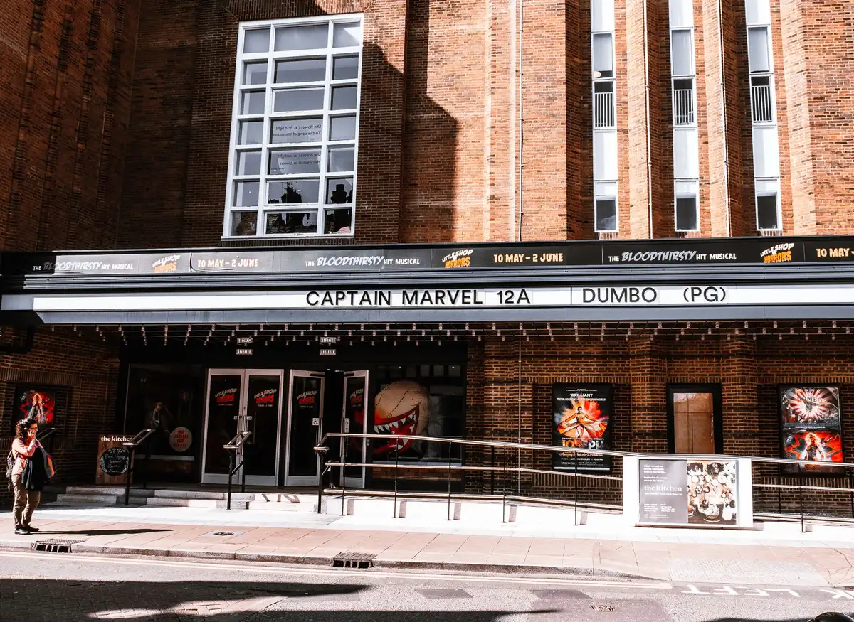 Fachada moderna de un cine con entrada principal y cartelera de películas