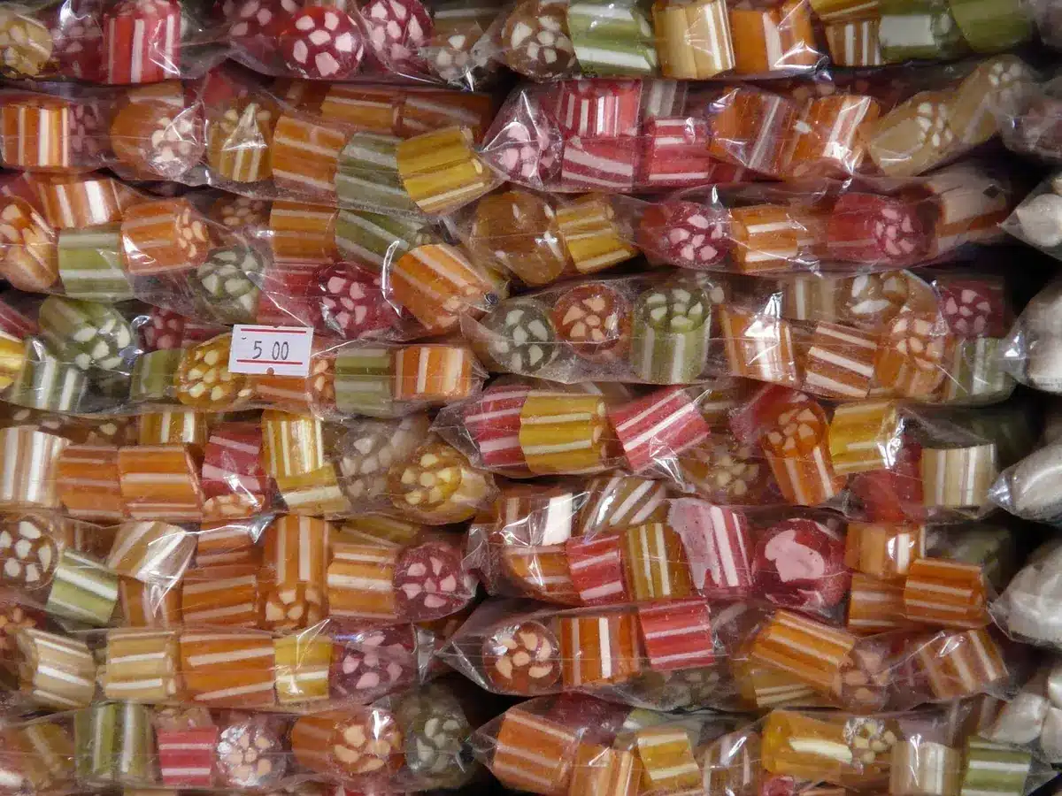 Bolsas de azúcar apiladas en un mercado local mostrando etiquetas de precio