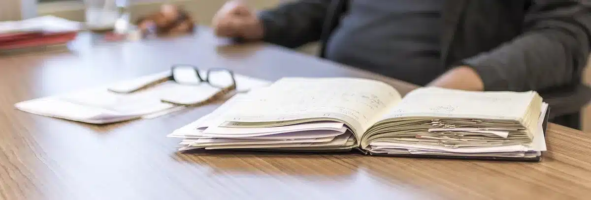 Mesa de comisión parlamentaria con documentos, micrófono y manos anónimas